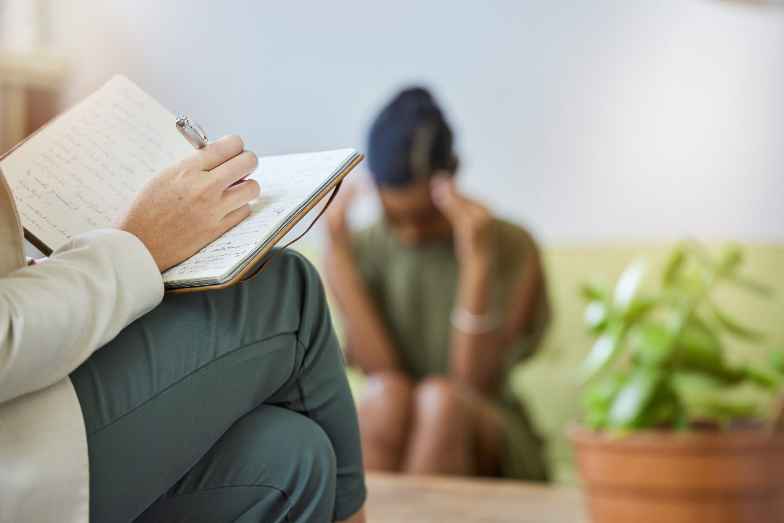 Therapy writing, psychologist and sad black woman with stress, headache and burnout in office. Support, therapist consultation and mental health check with psychology work of a patient on a sofa.